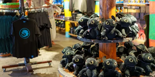 Blick in den Drachenzähmen-Shop im Heide Park Resort. Im Vordergrund sind Ohnezahn Plüschfiguren zu sehen und im Hintergrund T-Shirts.