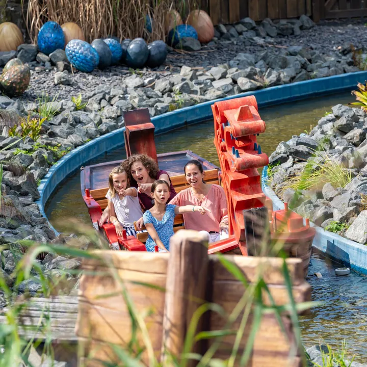 Zwei Frauen und zwei Mädchen sitzen im Wikingerboot und erkunden die Attraktion "Drachengrotte" im Heide Park Resort.