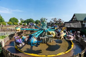 Kinder fahren in fliegenden Drachen über Wasser im Themenbereich „Drachenzähmen – Die Insel“ im Heide Park Resort.