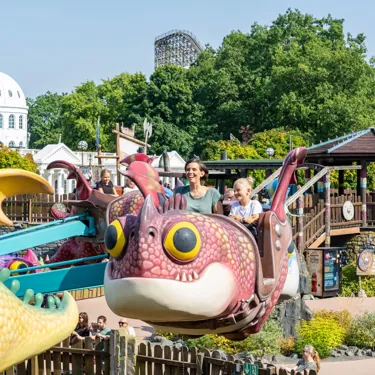 Kinder fahren in fliegenden Drachen über Wasser im Themenbereich „Drachenzähmen – Die Insel“ im Heide Park Resort.